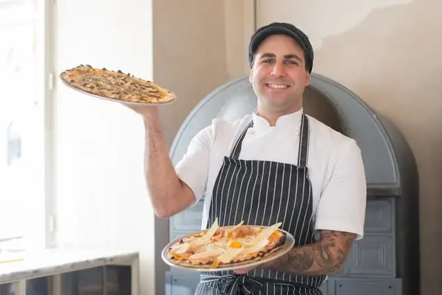 cook-holding-two-pizzas